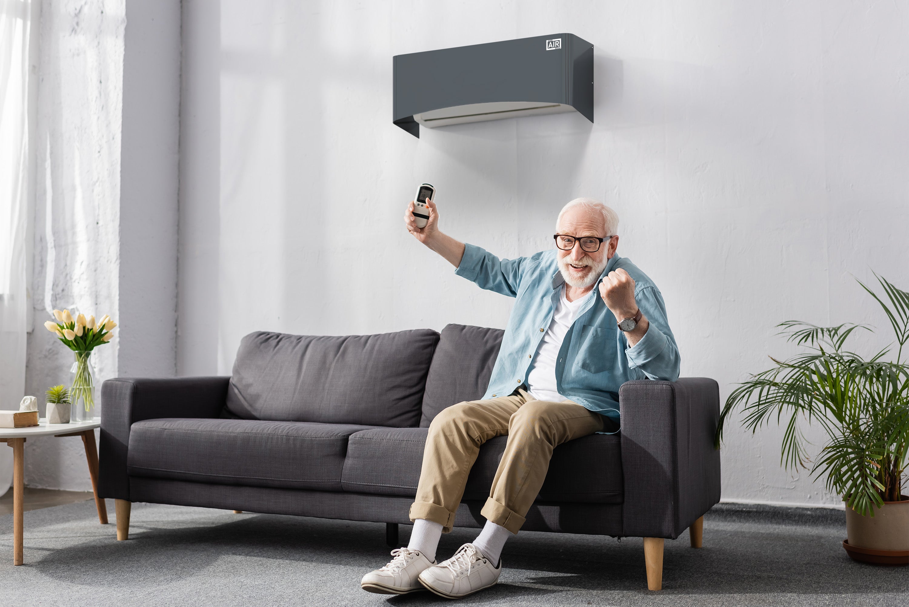 Zufriedener älterer Bewohner im nordischen Wohnzimmer – Clio Split Abdeckung anthrazit für Komfort und Eleganz. Kompatibel mit dem Split-Klimagerät Innenmodul Daikin ERLA-DV 06DV.