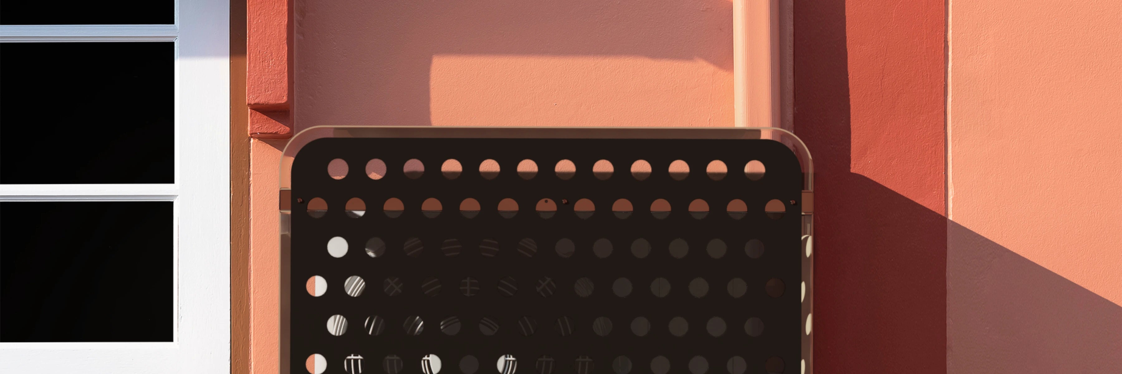 Copertura per condizionatore a muro in alluminio nero, ideale per protezione da pioggia e sole. Soluzione di design per unità esterna su parete color terracotta.