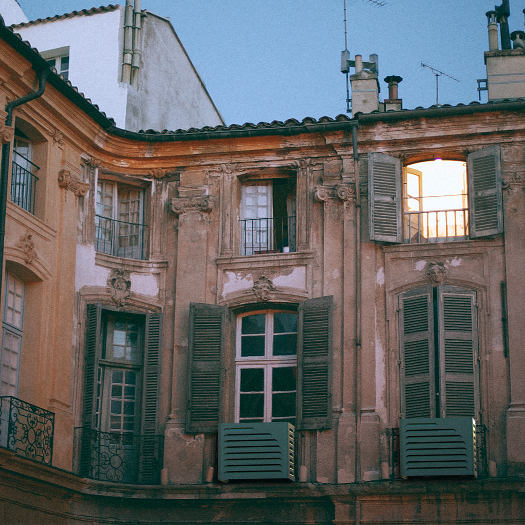 Curve anthracite AC cover installed under windows in European historic city apartments – elegant wall mounting. Cache posée sur unité extérieure Daikin Sensira, idéale en zone résidentielle urbaine.