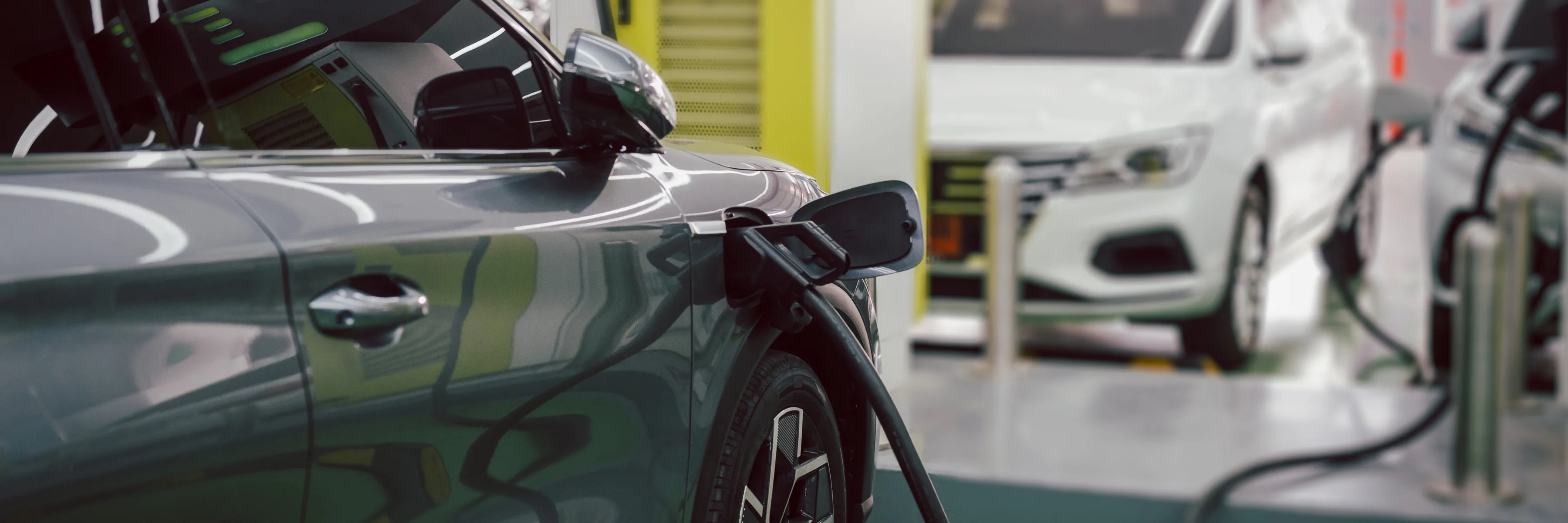 Nahaufnahme mehrerer Elektrofahrzeuge beim Laden in einem Unternehmensumfeld, mit sicherer und strukturierter Infrastruktur