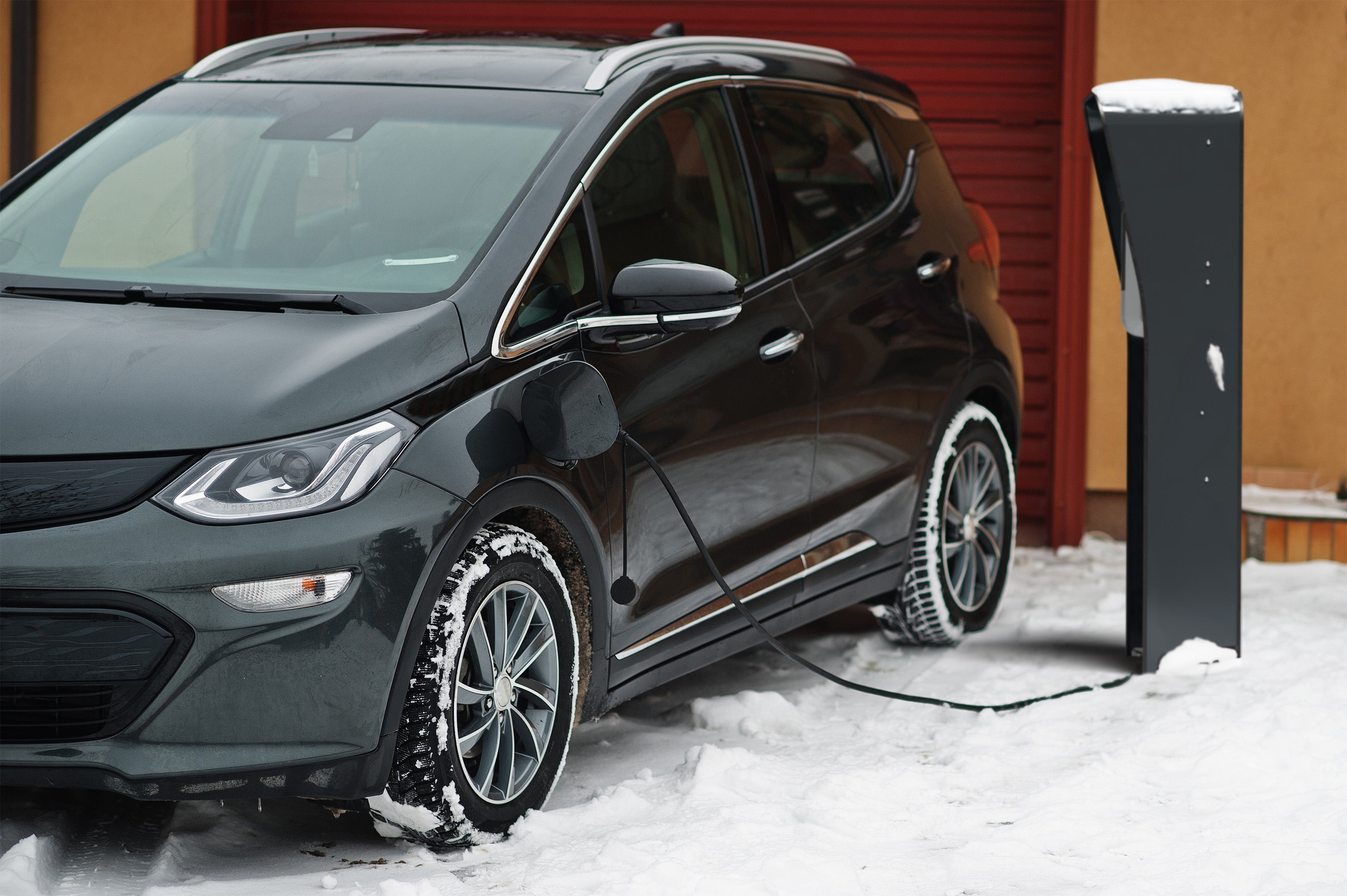 Elektroauto lädt trotz Schnee – Stand-Ladesäule schützt Wallbox vor Witterung, Reichweite des Kabels ideal dank freier Platzierung. Kompatibel mit der Wandladestation Enel X JuiceBox.
