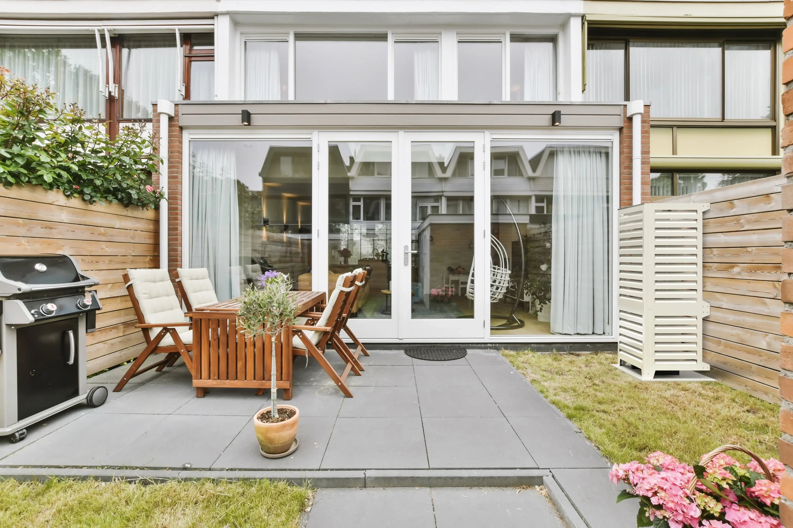 Beige Abdeckung für Wärmepumpe Panasonic WH-UXZ09KE8 im Hausgarten, sorgt für Schutz und bessere Fassadengestaltung.