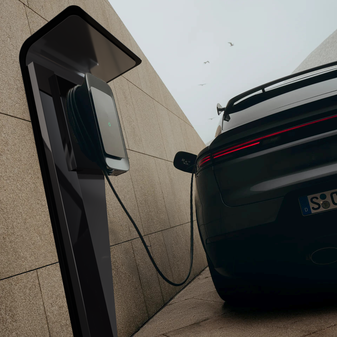 Colonne Vela avec borne Tesla Wall Connector – installation élégante pour voiture de luxe dans environnement brutaliste et naturel