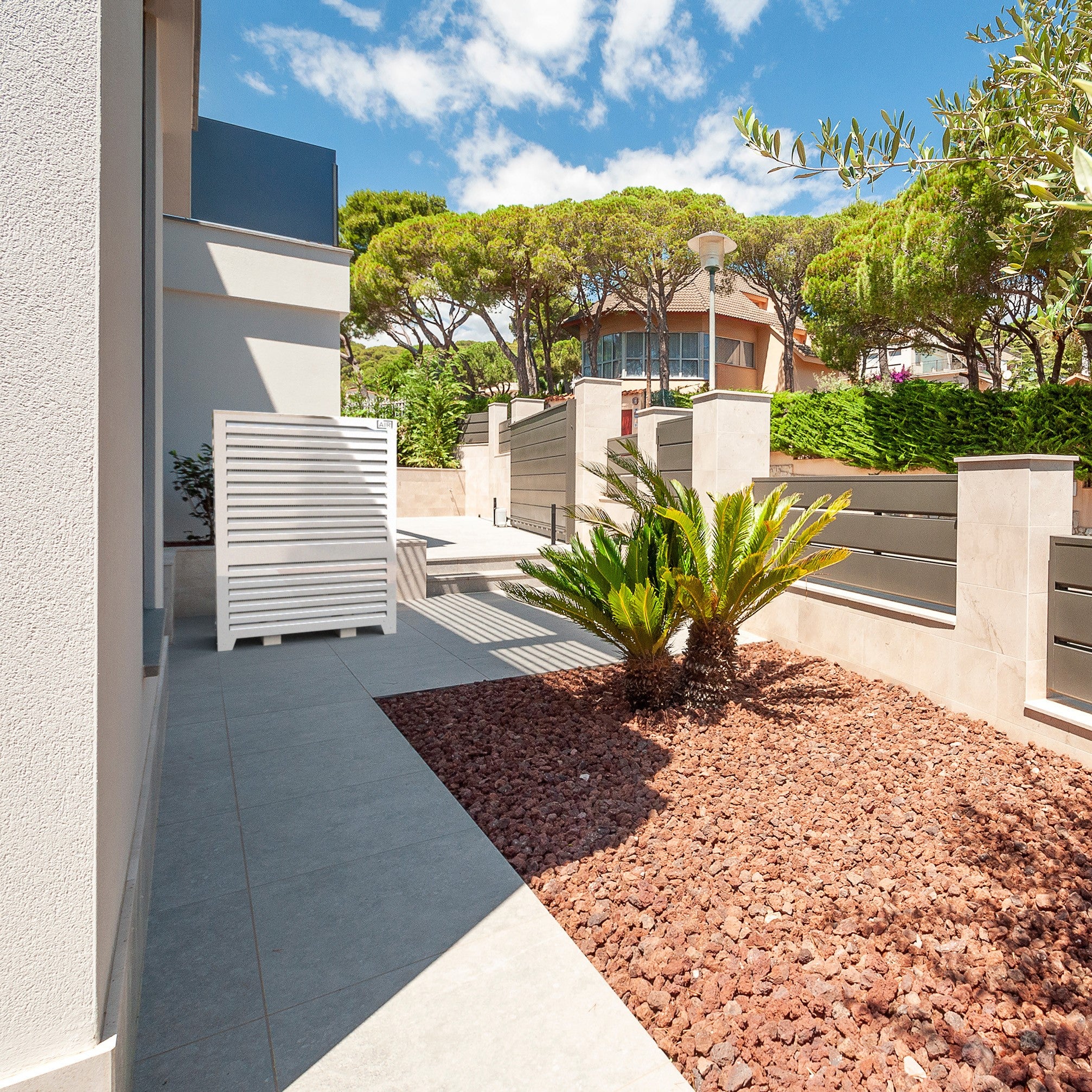 Modern white Big Blade heat pump cover installed in luxury courtyard with palm trees – sleek weather protection. engineered for energy-efficient systems like Daikin ERLA-DV 03DV.